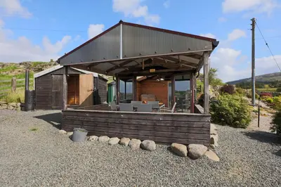 a small building with a roof on a gravel yard at Teapot Cottage in Newton Stewart