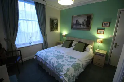 a bedroom with a bed with green walls and a window at Bluestones in Keswick