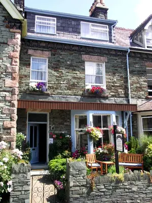 a brick house with a bench and flowers in front of it at Bluestones in Keswick