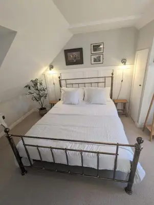 a bedroom with a large bed with white sheets and pillows at The Cottage @ 59 in Colmonell