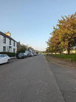 an empty street with cars parked on the side of the road at The Cottage @ 59 in Colmonell