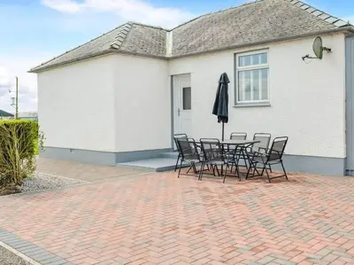 a table and chairs with an umbrella in front of a house at Paxville in Gretna