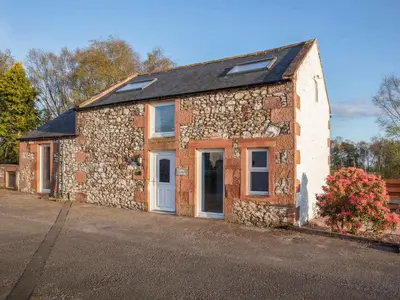a brick building with a white door on a street at Criffel Cottage in Ruthwell