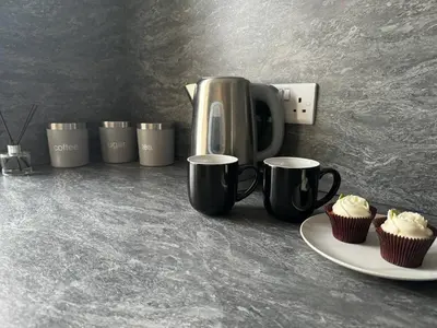 a counter with a coffee pot and cupcakes on a plate at The Lowther Penthouse - 2 Bedrooms - Sleeps 4 in Whitehaven