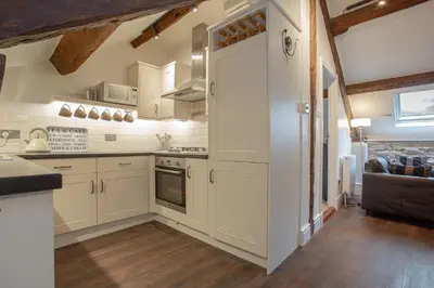 a kitchen with white cabinets and wooden floors at Goody Bridge Barn in Grasmere