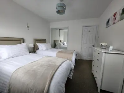 a bedroom with two beds and a dresser at 10 Ladyknowe court in Moffat