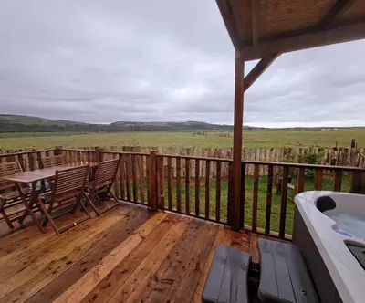 a deck with a table and chairs and a bath tub at The Galloway Steading - The Herons Nest, secure garden and with Hot Tub and Fire Pit in Glenluce