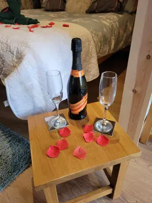 a table with a bottle of wine and two glasses at The Galloway Steading - The Herons Nest, secure garden and with Hot Tub and Fire Pit in Glenluce