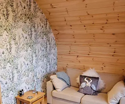 a living room with a couch and a wooden wall at The Galloway Steading - The Herons Nest, secure garden and with Hot Tub and Fire Pit in Glenluce