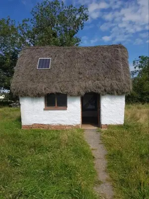 a house with a thatched roof with a pathway at Church House Barn Lake District & Solway Coast with Solway Firth views in Silloth