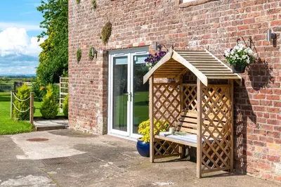 a wooden gazebo sitting outside of a brick building at Church House Barn Lake District & Solway Coast with Solway Firth views in Silloth