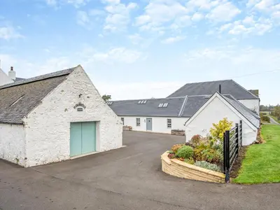 a large white building with a garage in a driveway at The Byre - Uk45343 in Ayr