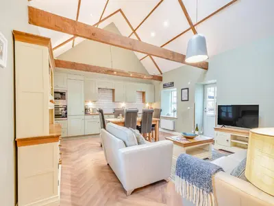 a living room with a white couch and a kitchen at The Byre - Uk45343 in Ayr