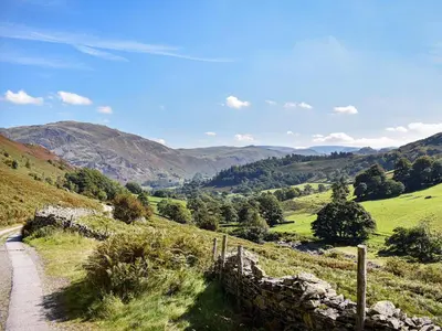 a dirt road in a field with mountains in the background at Striding Edge Cottage in Glenridding