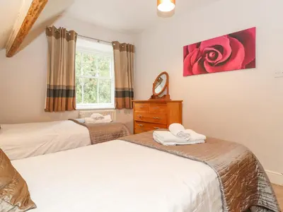 a bedroom with two beds and a red rose on the wall at Riverbank in Ambleside