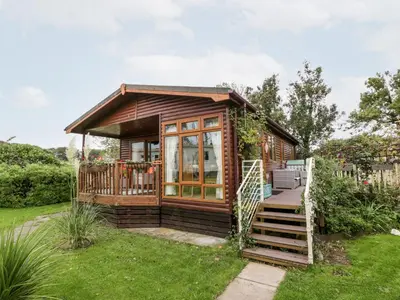 a tiny house with a porch and a deck at Eden Lodge in Newton Stewart