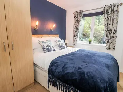 a bedroom with a large bed and a window at Eden Lodge in Newton Stewart