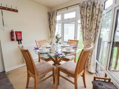 a dining room with a glass table and chairs at Eden Lodge in Newton Stewart