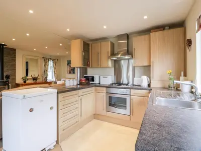 a kitchen with wooden cabinets and a white appliance at Eden Lodge in Newton Stewart