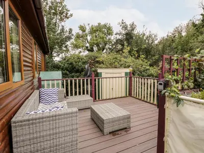 a wooden deck with wicker furniture on a house at Eden Lodge in Newton Stewart