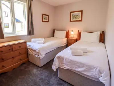 two twin beds in a room with a window at Mallard Cottage Lake District, Leisure Spa Pool & Gym in Penruddock