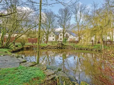 a pond in front of a house with ducks in it at Mallard Cottage Lake District, Leisure Spa Pool & Gym in Penruddock