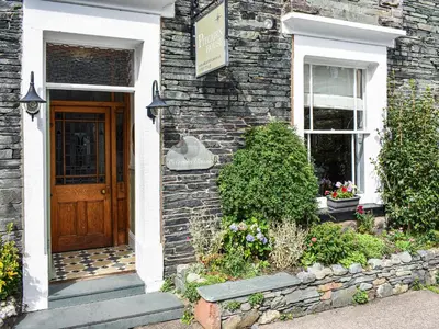 a brick house with a wooden door and a window at Pitcairn Cottage-Uk41256 in Keswick