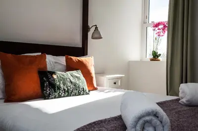 a bedroom with a bed with orange pillows and a window at Stunning Scottish Hot Tub Getaway in Gatehouse of Fleet
