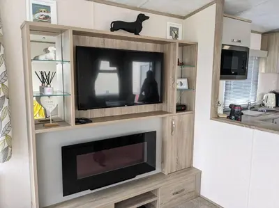 a entertainment center with a flat screen tv in a living room at Beautiful Pet Friendly Southerness Caravan With Sea View & Decking Area in Mainsriddle