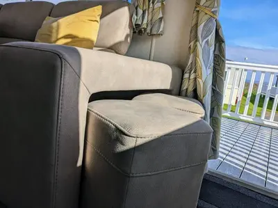 a couch sitting on top of a balcony at Beautiful Pet Friendly Southerness Caravan With Sea View & Decking Area in Mainsriddle