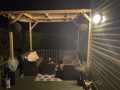 a pergola on a deck with chairs and plants at Inglenook Caravan in Lamplugh