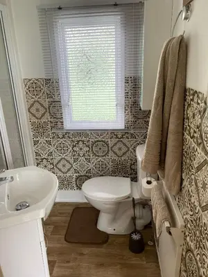 a bathroom with a toilet and a sink and a window at Inglenook Caravan in Lamplugh