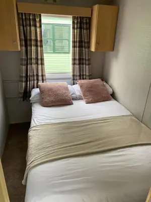 a bed in a small room with a window at Inglenook Caravan in Lamplugh