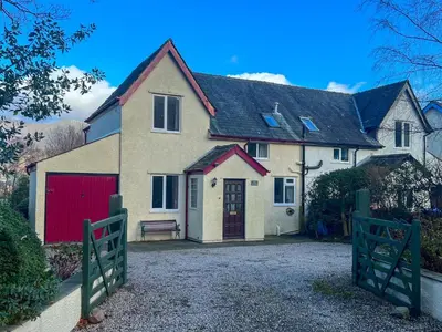 a large house with a red garage and a gate at Hill Cottage, Braithwaite with garden and fell views, dog friendly walks from the door, close to Bassenthwaite in Braithwaite