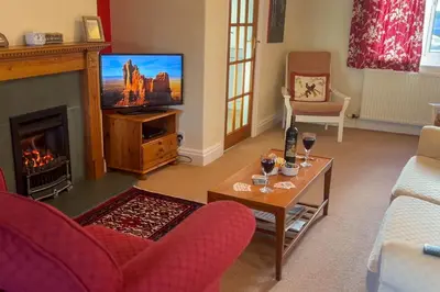 a living room with a fireplace and a tv at Hill Cottage, Braithwaite with garden and fell views, dog friendly walks from the door, close to Bassenthwaite in Braithwaite