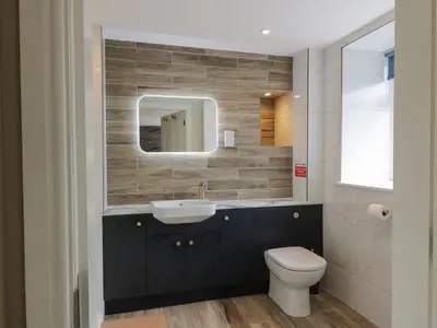 a bathroom with a sink and a toilet and a mirror at Hardhills Cottage in Castle Douglas