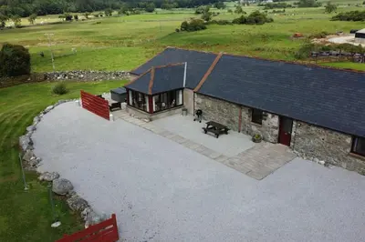 an aerial view of a house with a dog in front of it at Middle Byre at Clauchan Holiday Cottages in Gatehouse of Fleet