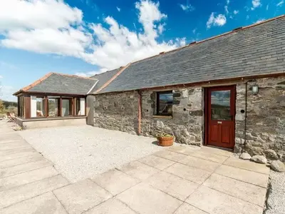 a stone house with a red door and a patio at Middle Byre at Clauchan Holiday Cottages in Gatehouse of Fleet