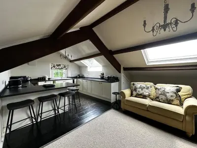 a kitchen with a couch and some bar stools at Penthouse apartment in Cockermouth