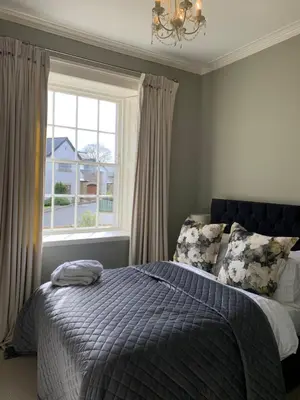 a bedroom with a bed with a blue comforter and a window at Penthouse apartment in Cockermouth