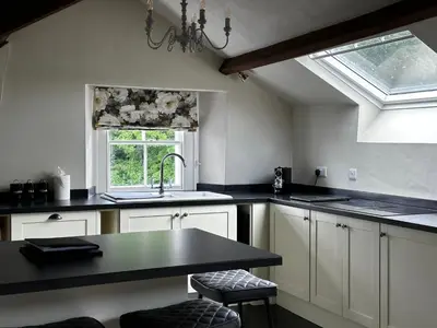 a kitchen with white cabinets and a sink and a window at Penthouse apartment in Cockermouth