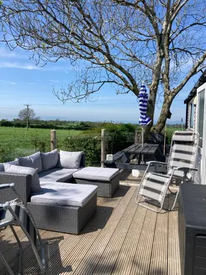 a patio with a couch and chairs and a tree at Lake District Solway View 16 The Beeches Caravan Park in Gilcrux