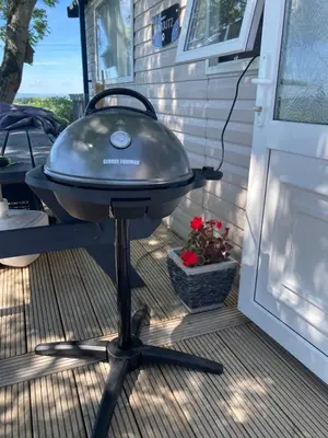 a grill on a patio next to a door at Lake District Solway View 16 The Beeches Caravan Park in Gilcrux