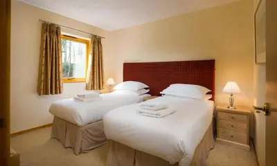 a bedroom with two beds with white sheets at Keswick Bridge Lodge Resort in Keswick