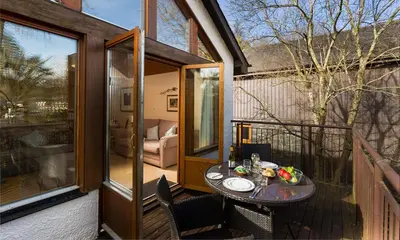 a small table on the balcony of a house at Keswick Bridge Lodge Resort in Keswick