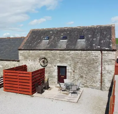 a brick building with a table and chairs in front of it at The Barn @ Clauchan holiday Cottages in Gatehouse of Fleet