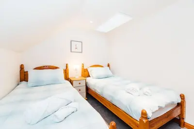 two twin beds in a room with white sheets at The Barn @ Clauchan holiday Cottages in Gatehouse of Fleet