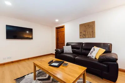 a living room with a leather couch and a table at The Barn @ Clauchan holiday Cottages in Gatehouse of Fleet