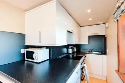 a kitchen with white cabinets and a microwave at The Stable at Clauchan Holiday Cottages in Gatehouse of Fleet