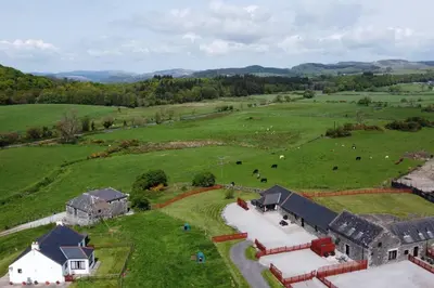 an aerial view of a farm with cows in a field at The Stable at Clauchan Holiday Cottages in Gatehouse of Fleet